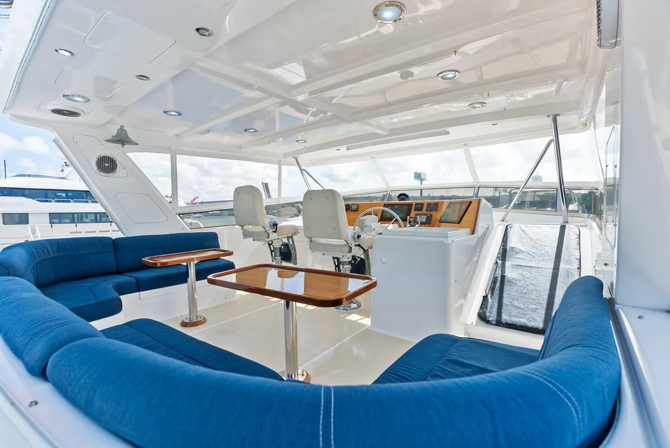 The flybridge offers spacious seating with plush blue cushions and a well-equipped helm station. aboard EL LEGADO Yacht for Sale