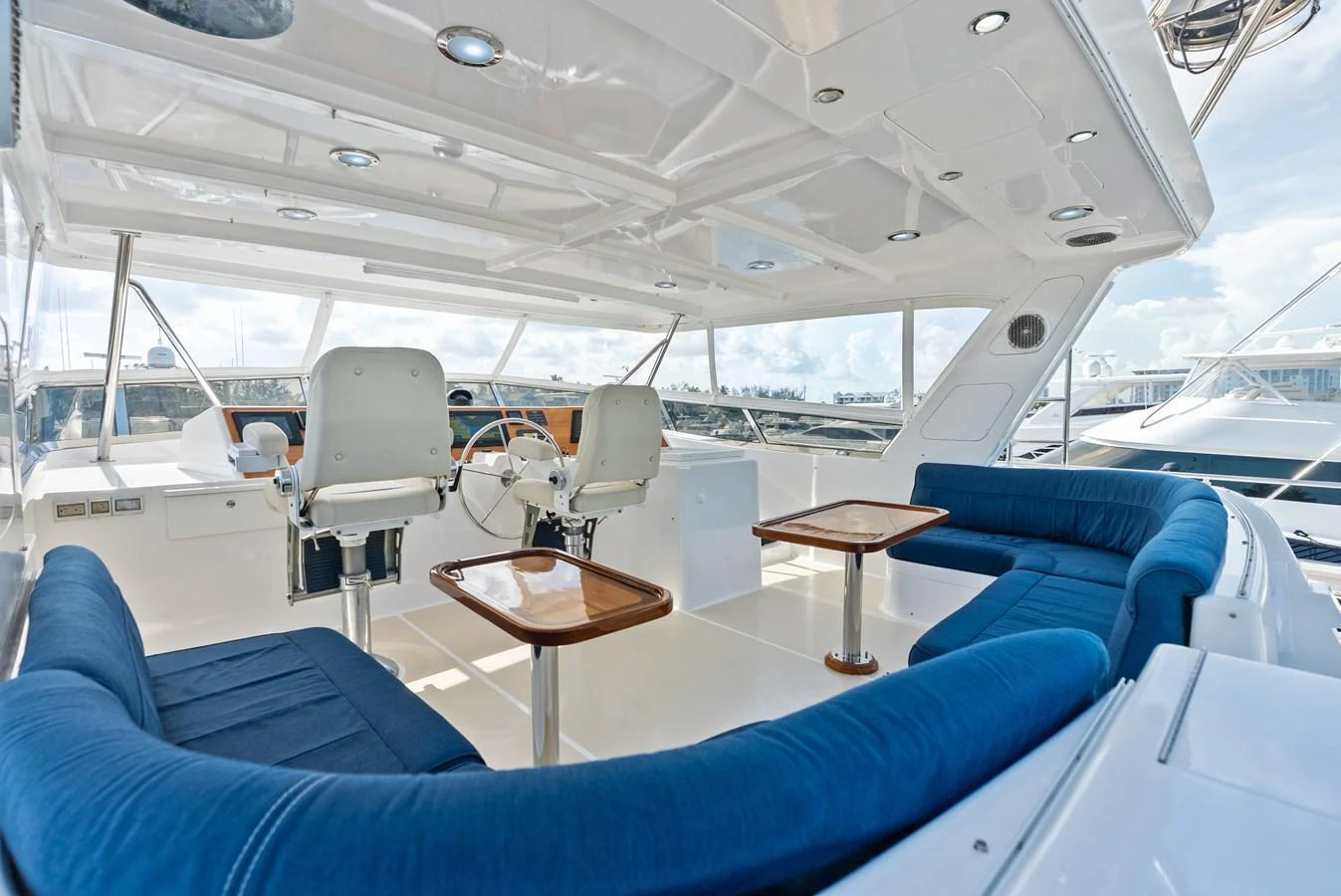 The flybridge features spacious seating with plush blue cushions and a well-equipped helm station. aboard EL LEGADO Yacht for Sale