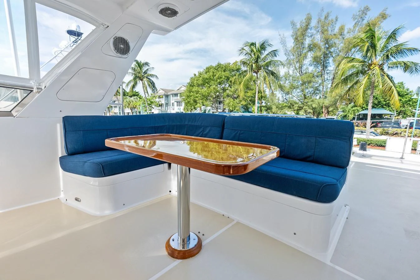 The aft deck features a comfortable seating area with a polished wooden table, perfect for outdoor relaxation. aboard EL LEGADO Yacht for Sale