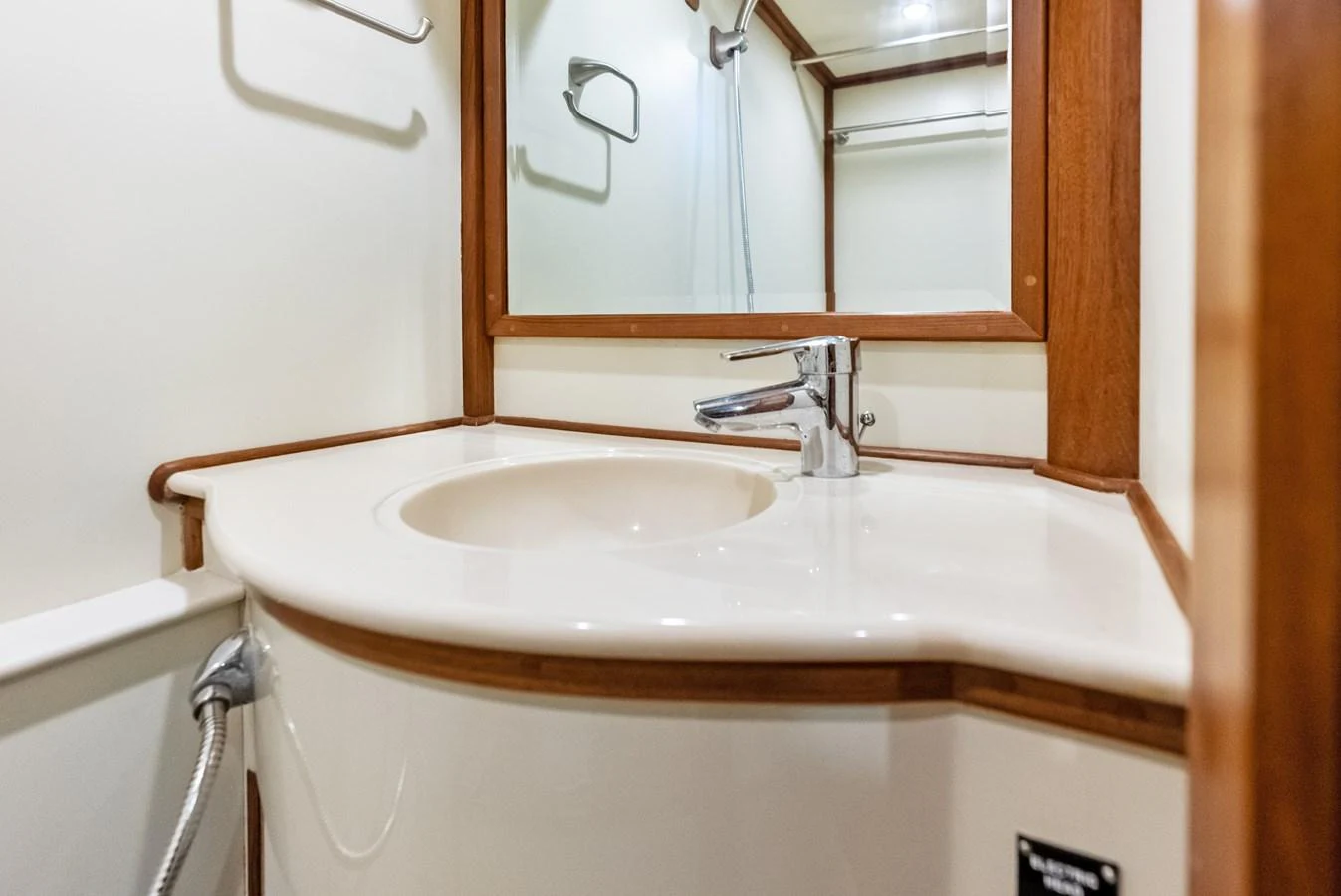 The yacht's bathroom features a sleek sink with a modern faucet and a large mirror. aboard EL LEGADO Yacht for Sale
