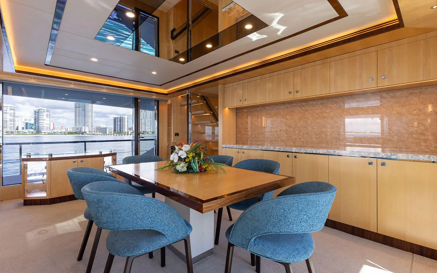 The yacht's dining area features a spacious table with elegant blue chairs and panoramic windows offering stunning views. aboard WADDLE WE DO Yacht for Sale