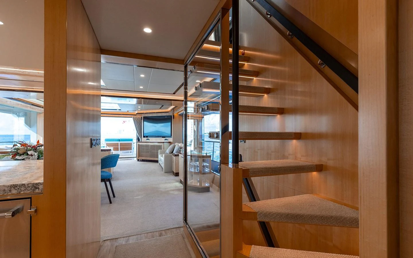 The yacht's salon features a modern staircase, plush seating, and large windows for natural light. aboard WADDLE WE DO Yacht for Sale