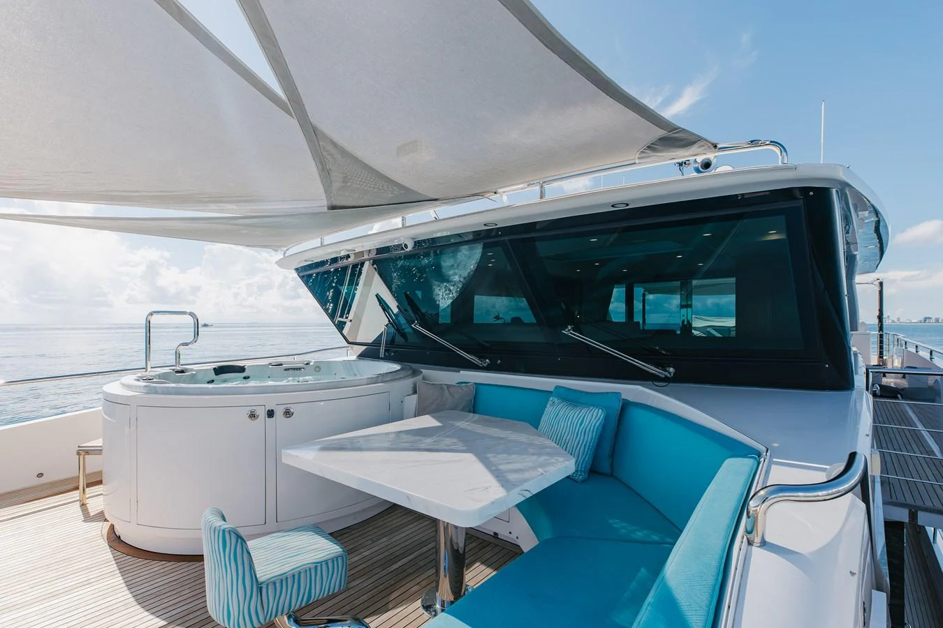 The flybridge offers a luxurious seating area with a table and a jacuzzi, perfect for relaxation and enjoying the view. aboard WADDLE WE DO Yacht for Sale