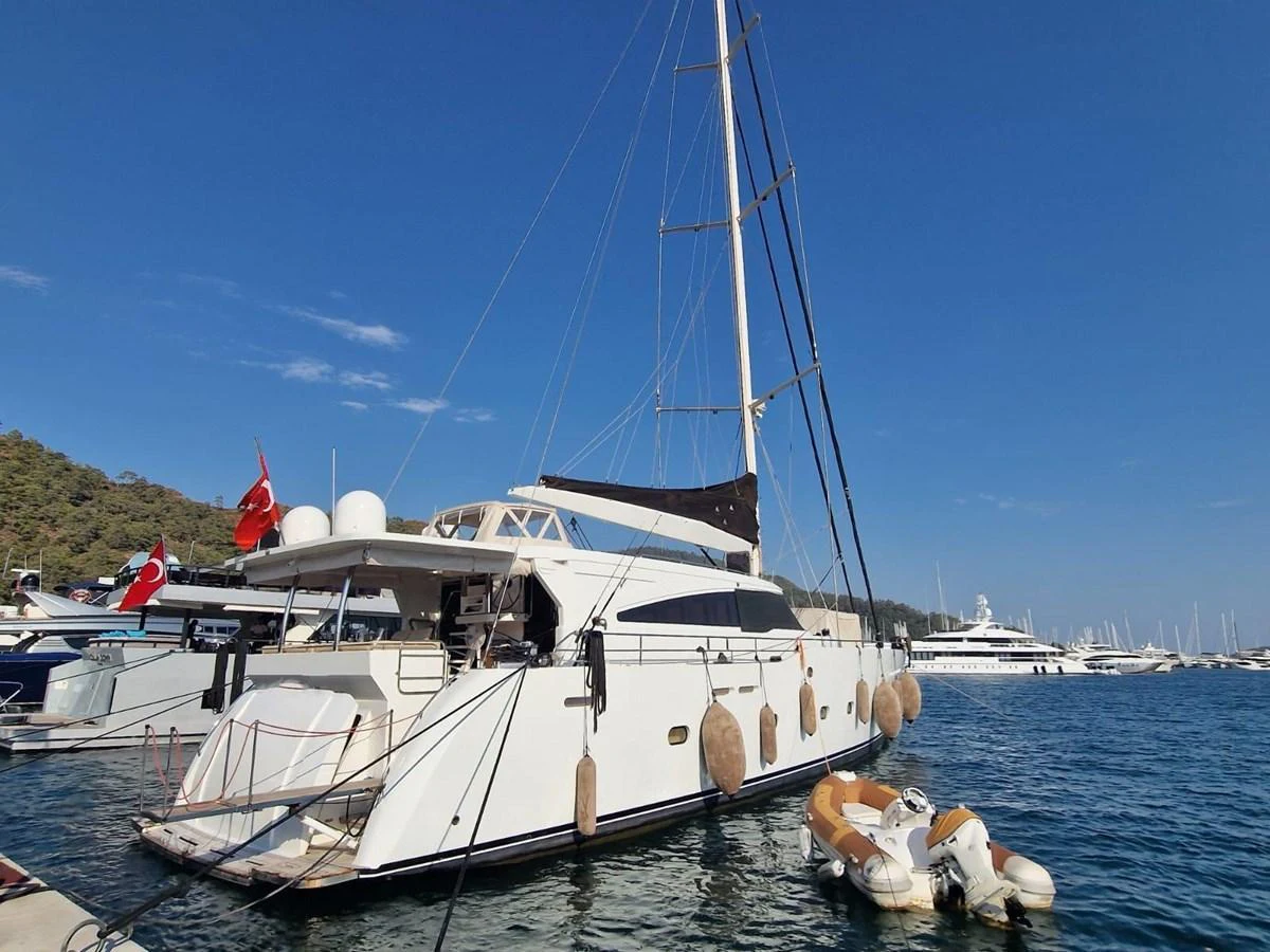 A sleek yacht docked at a marina, showcasing its elegant design and spacious deck. aboard 23 M MOTORSAILOR Yacht for Sale