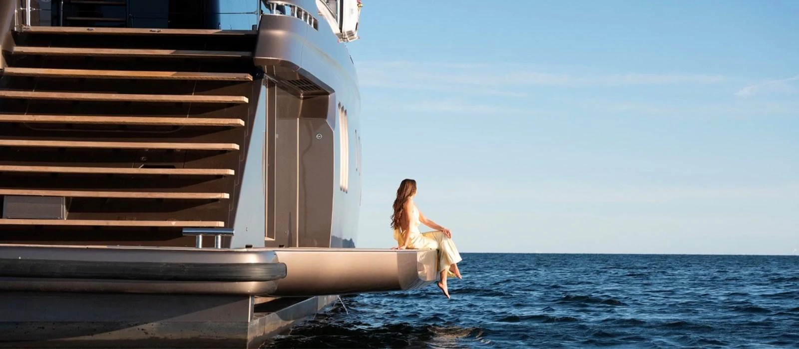 A serene moment on the yacht's swim platform with a woman enjoying the ocean view. aboard TWILIGHT Yacht for Sale