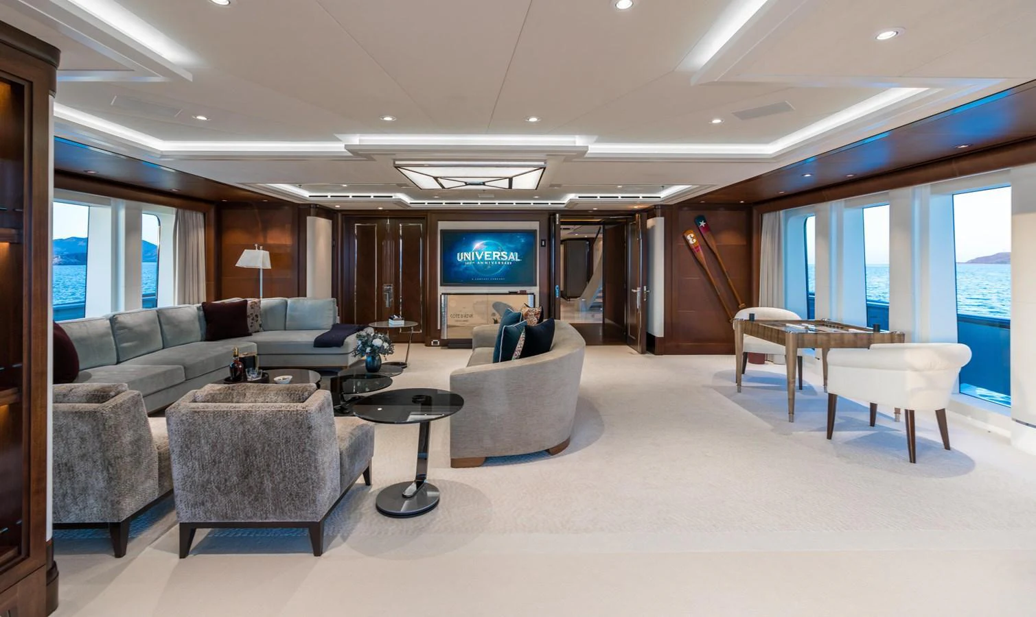 The spacious salon features luxurious seating, a large TV, and panoramic windows offering stunning ocean views. aboard HAMPSHIRE Yacht for Sale