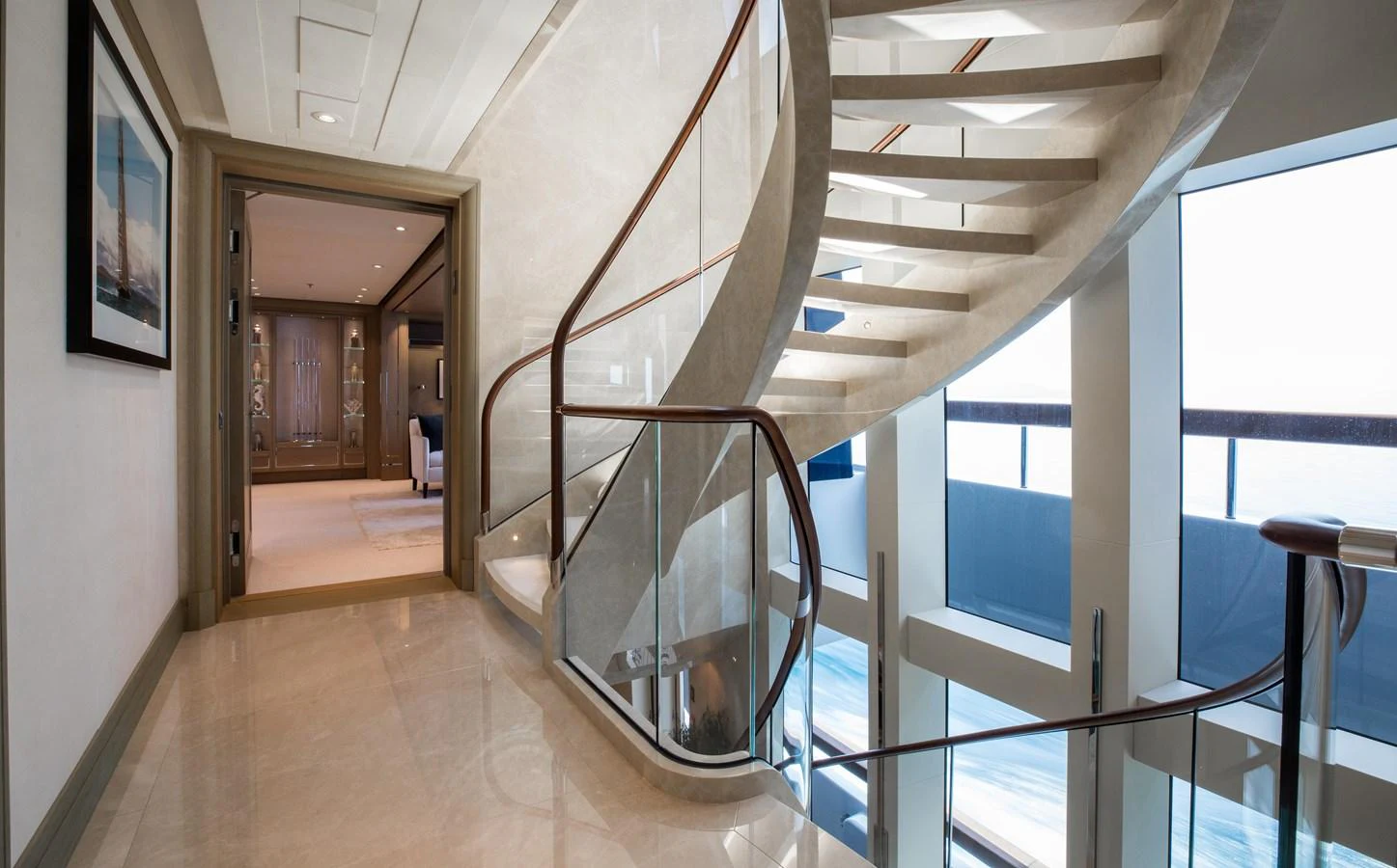 A luxurious interior staircase with elegant design and large windows offering stunning ocean views. aboard HAMPSHIRE Yacht for Sale