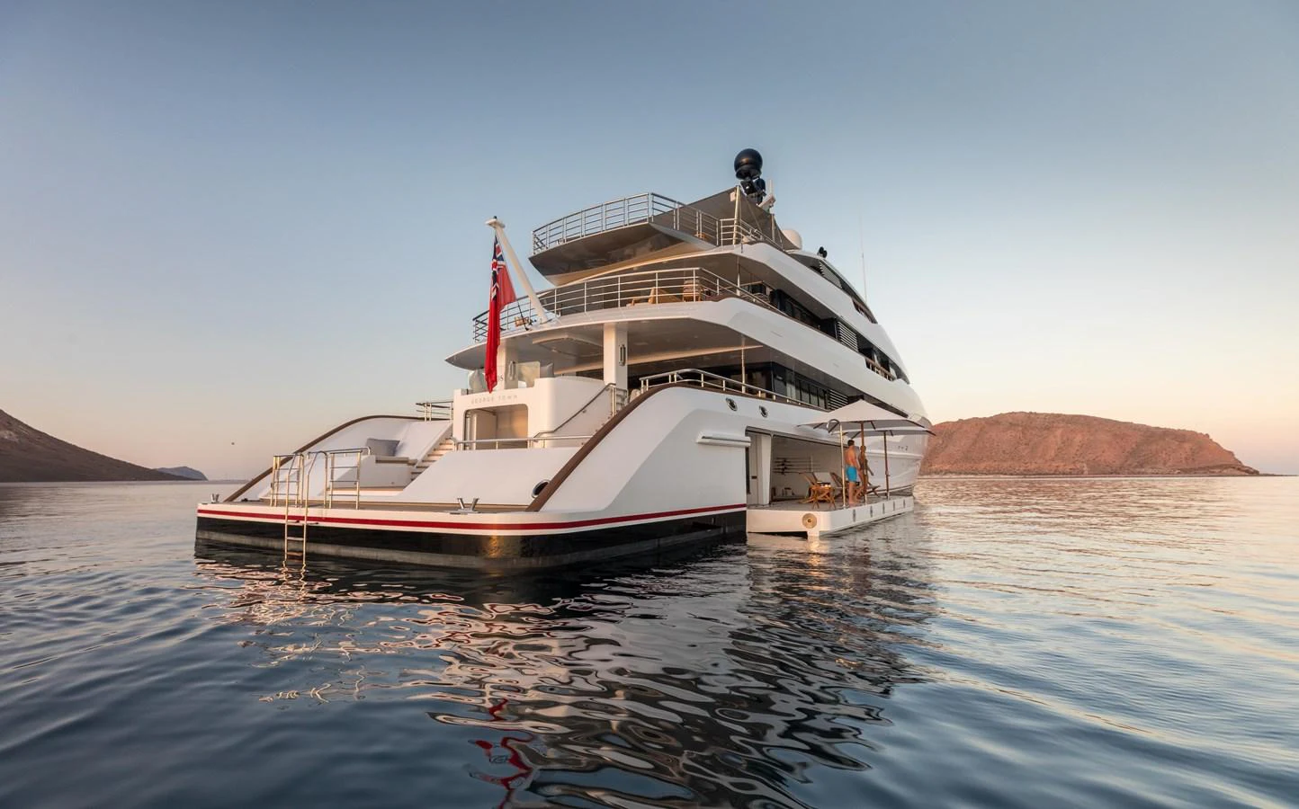 A luxurious yacht is anchored in calm waters against a serene backdrop of distant hills. aboard HAMPSHIRE Yacht for Sale