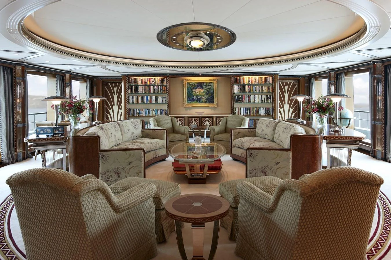 The salon features elegant seating arrangements with luxurious decor and a well-stocked bookshelf. aboard LADY CHRISTINE Yacht for Sale