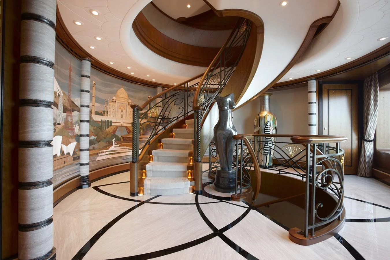 The yacht's interior features an elegant staircase with intricate railings and a mural backdrop, exuding luxury and sophistication. aboard LADY CHRISTINE Yacht for Sale