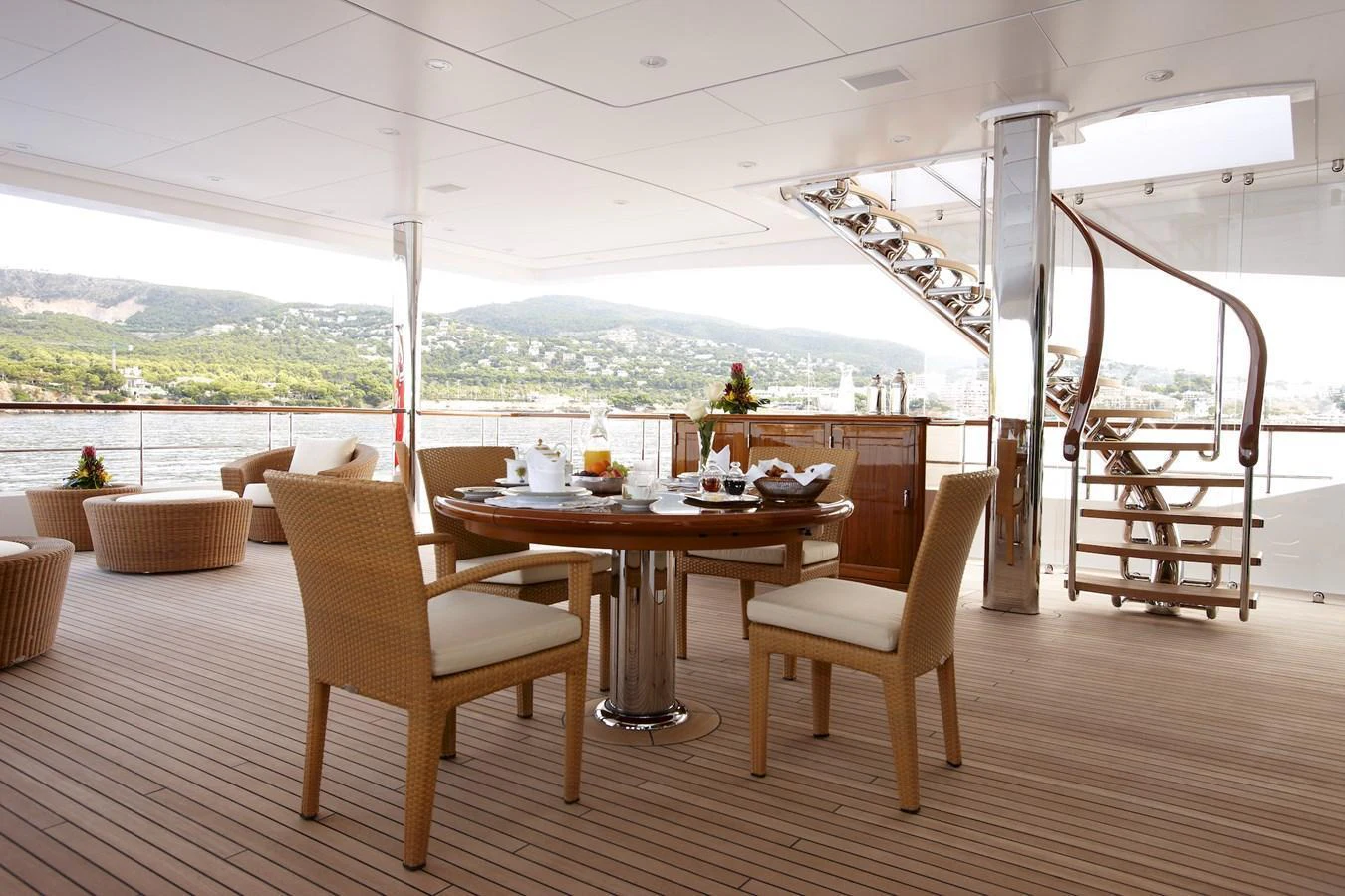 The aft deck features a stylish dining area with wicker chairs and a polished wooden table, perfect for alfresco meals. aboard LADY CHRISTINE Yacht for Sale