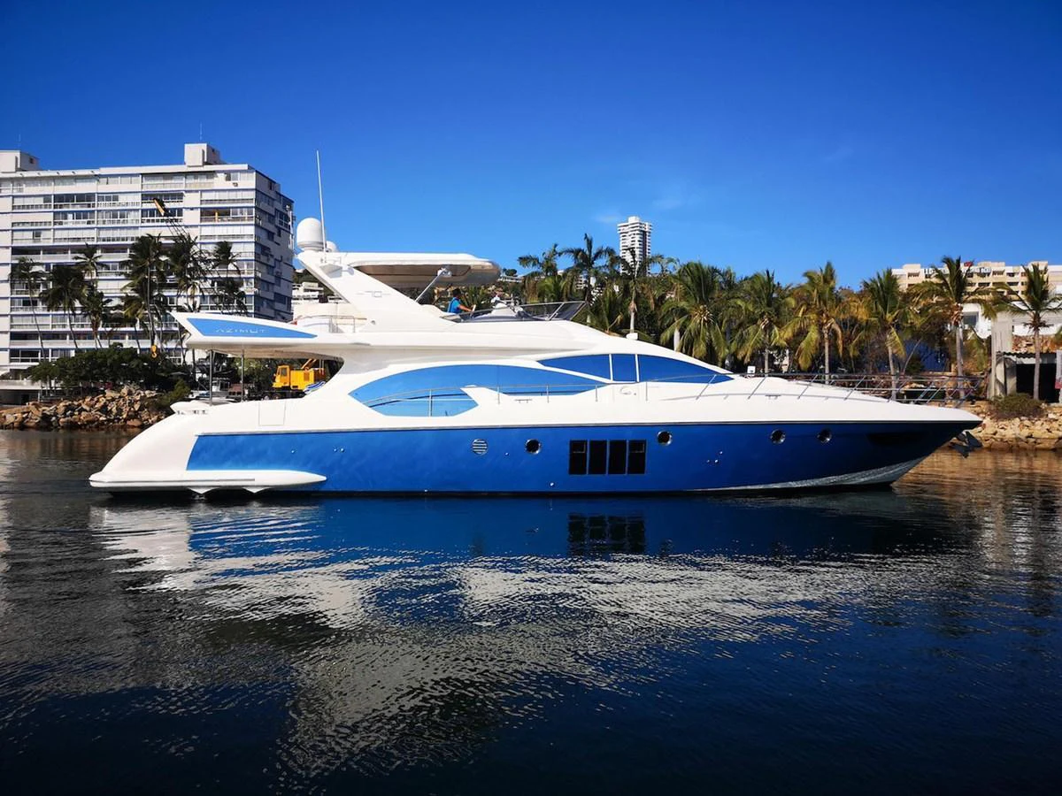 A sleek and modern yacht is docked in a serene marina with a backdrop of palm trees and buildings. aboard NE SEL Yacht for Sale