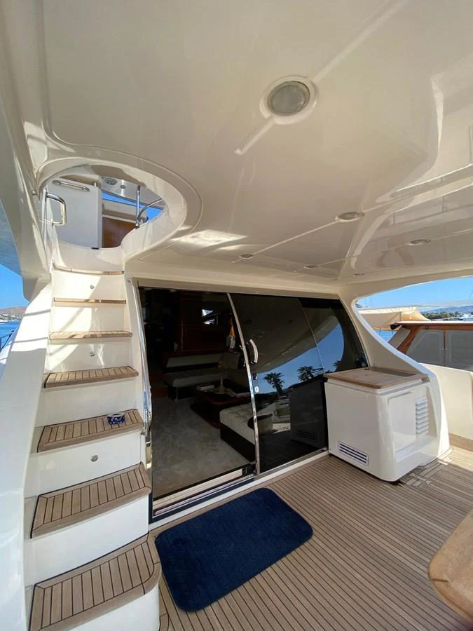 The aft deck features a staircase leading to the upper deck and a sliding glass door to the interior. aboard NE SEL Yacht for Sale