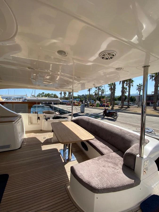 The aft deck features a comfortable seating area with a table, perfect for outdoor relaxation and dining. aboard NE SEL Yacht for Sale