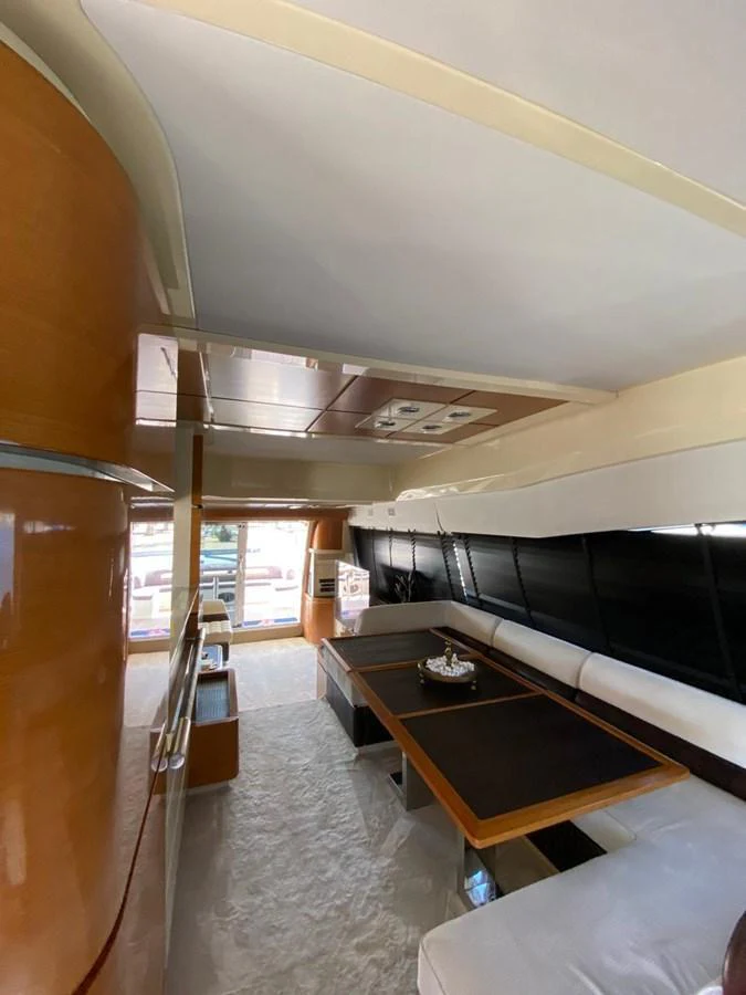 The yacht's interior features a cozy seating area with a table, complemented by sleek wood finishes and ample natural light. aboard NE SEL Yacht for Sale