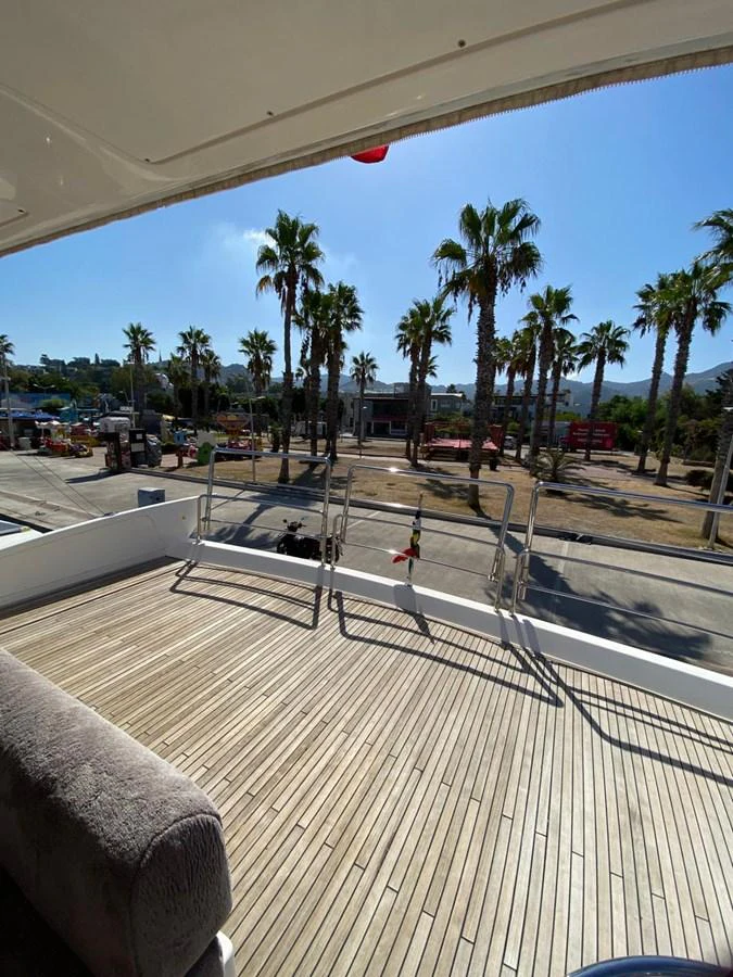 The yacht's deck offers a spacious and inviting area with a view of palm trees and a coastal setting. aboard NE SEL Yacht for Sale