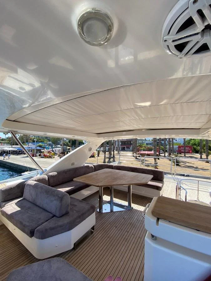 The flybridge offers a spacious seating area with plush cushions and a wooden table, perfect for outdoor relaxation. aboard NE SEL Yacht for Sale