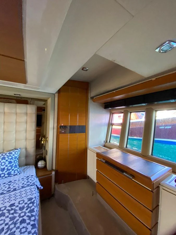 The stateroom features a cozy bed with patterned linens and ample natural light from large windows. aboard NE SEL Yacht for Sale