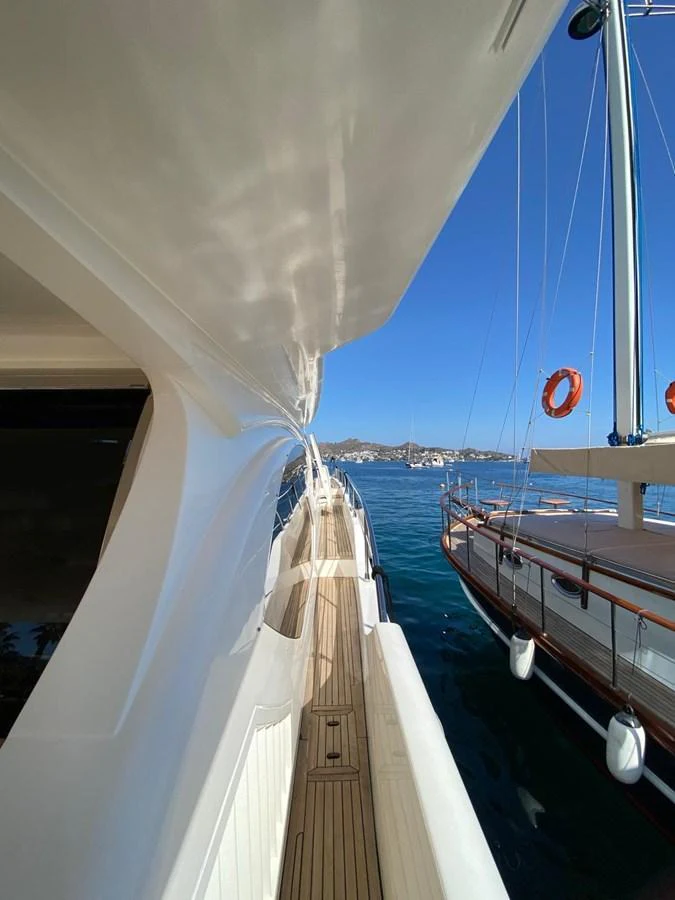 A sleek side deck of a yacht with a view of the water and another vessel nearby. aboard NE SEL Yacht for Sale