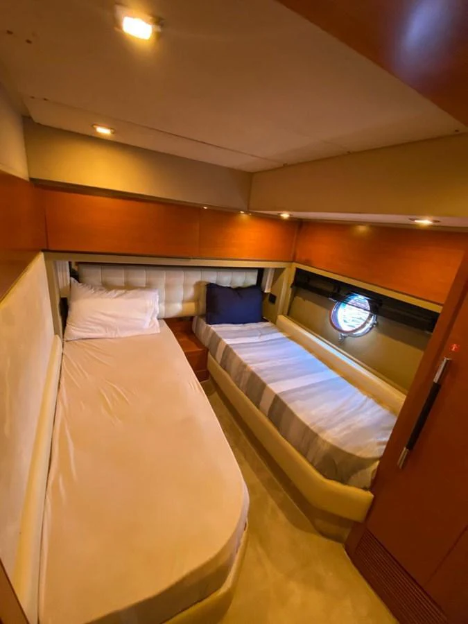 The cozy twin stateroom features two single beds with elegant bedding and warm ambient lighting. aboard NE SEL Yacht for Sale
