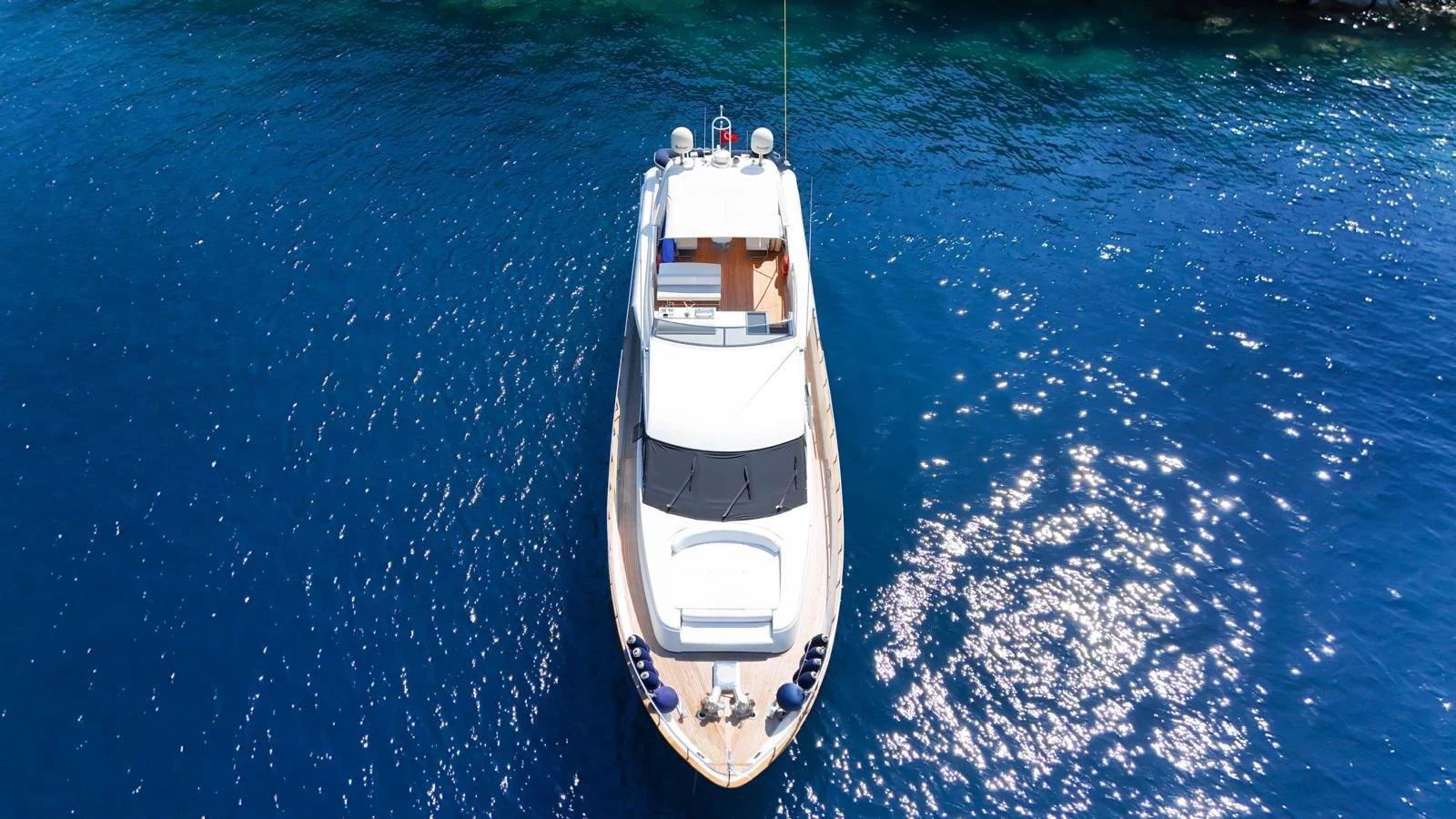 A stunning aerial view of a sleek yacht cruising on clear blue waters. aboard TWINS PC Yacht for Sale