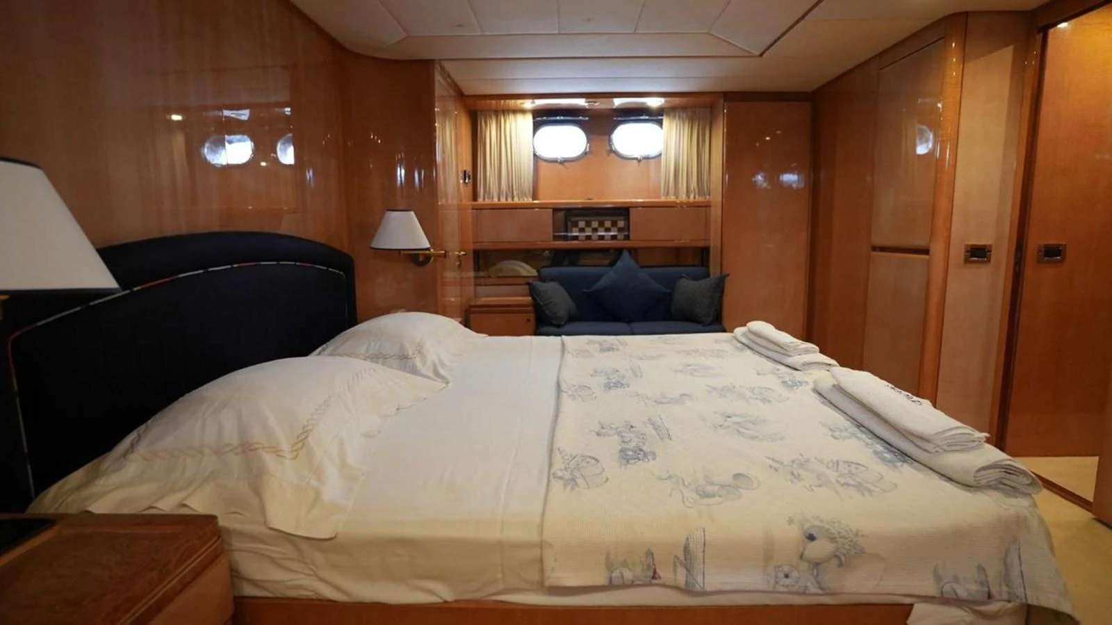 The stateroom features a comfortable bed with elegant wooden paneling and soft lighting. aboard TWINS PC Yacht for Sale