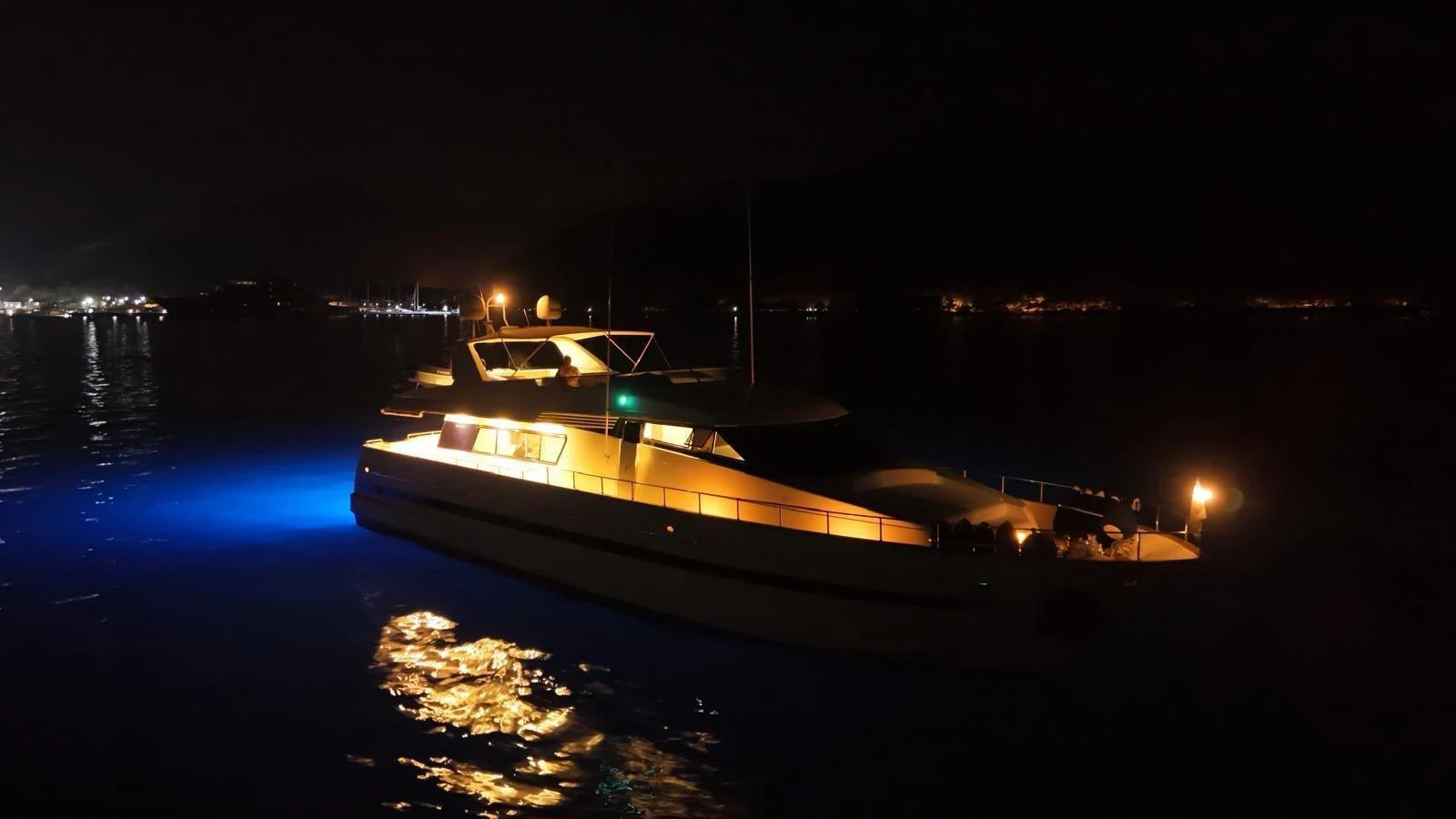 A yacht is beautifully illuminated at night, casting a serene glow on the water. aboard TWINS PC Yacht for Sale