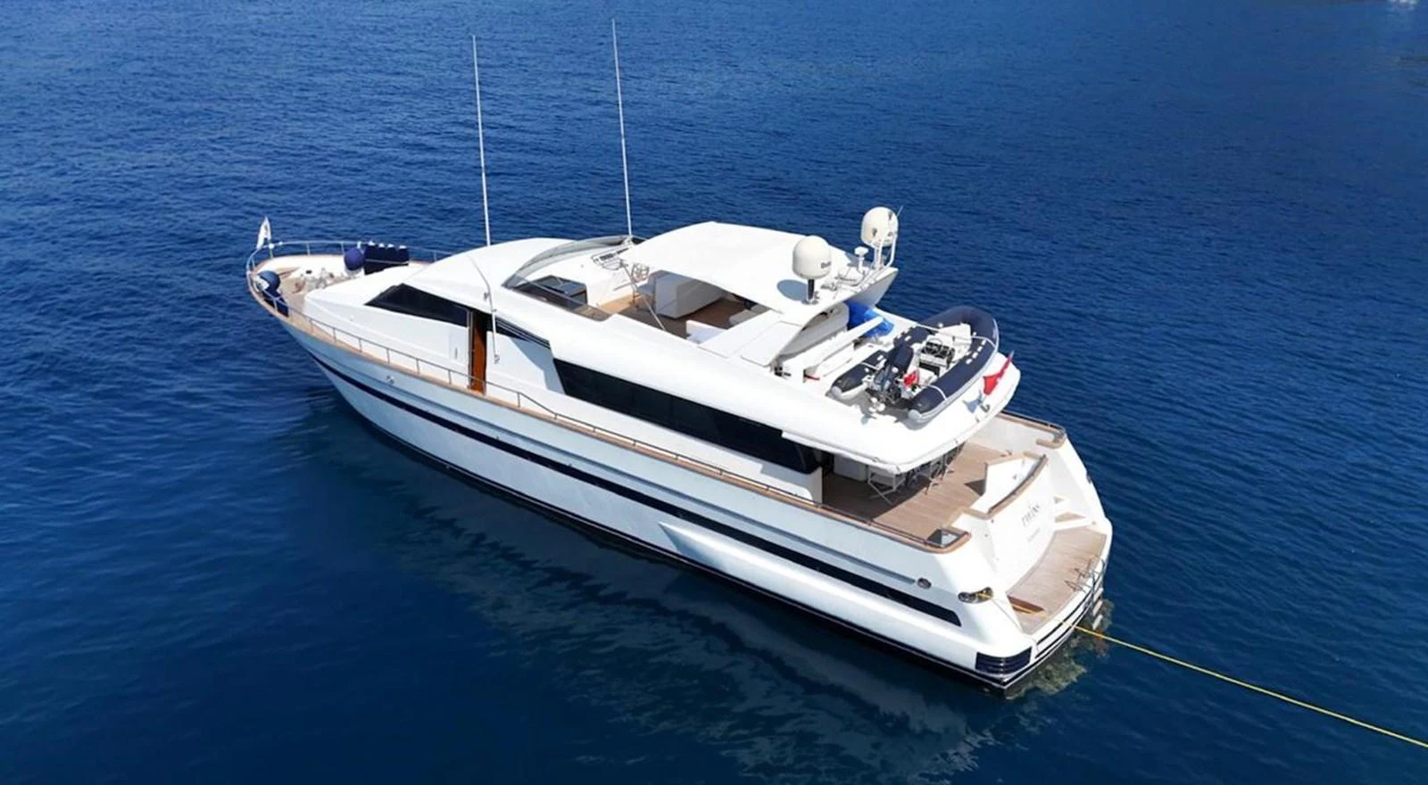 A sleek and modern yacht is anchored in calm blue waters, showcasing its elegant design and spacious deck areas. aboard TWINS PC Yacht for Sale