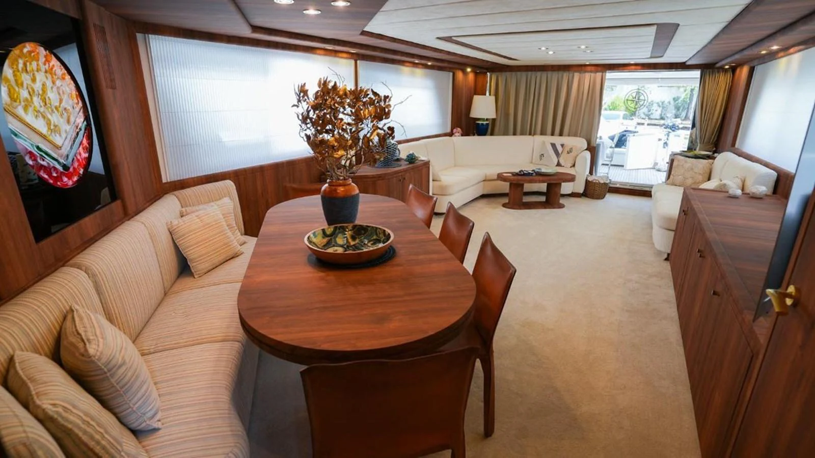 The salon features a spacious and elegantly designed seating and dining area with warm wooden accents. aboard TWINS PC Yacht for Sale