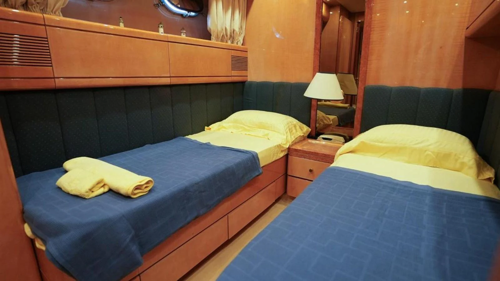 The twin stateroom features two single beds with blue and yellow bedding, offering a cozy and inviting atmosphere. aboard TWINS PC Yacht for Sale