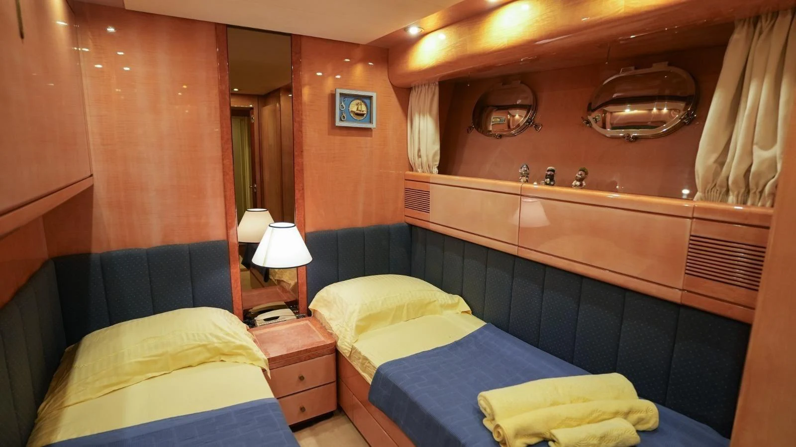 The twin stateroom features cozy twin beds with elegant wood paneling and soft lighting. aboard TWINS PC Yacht for Sale