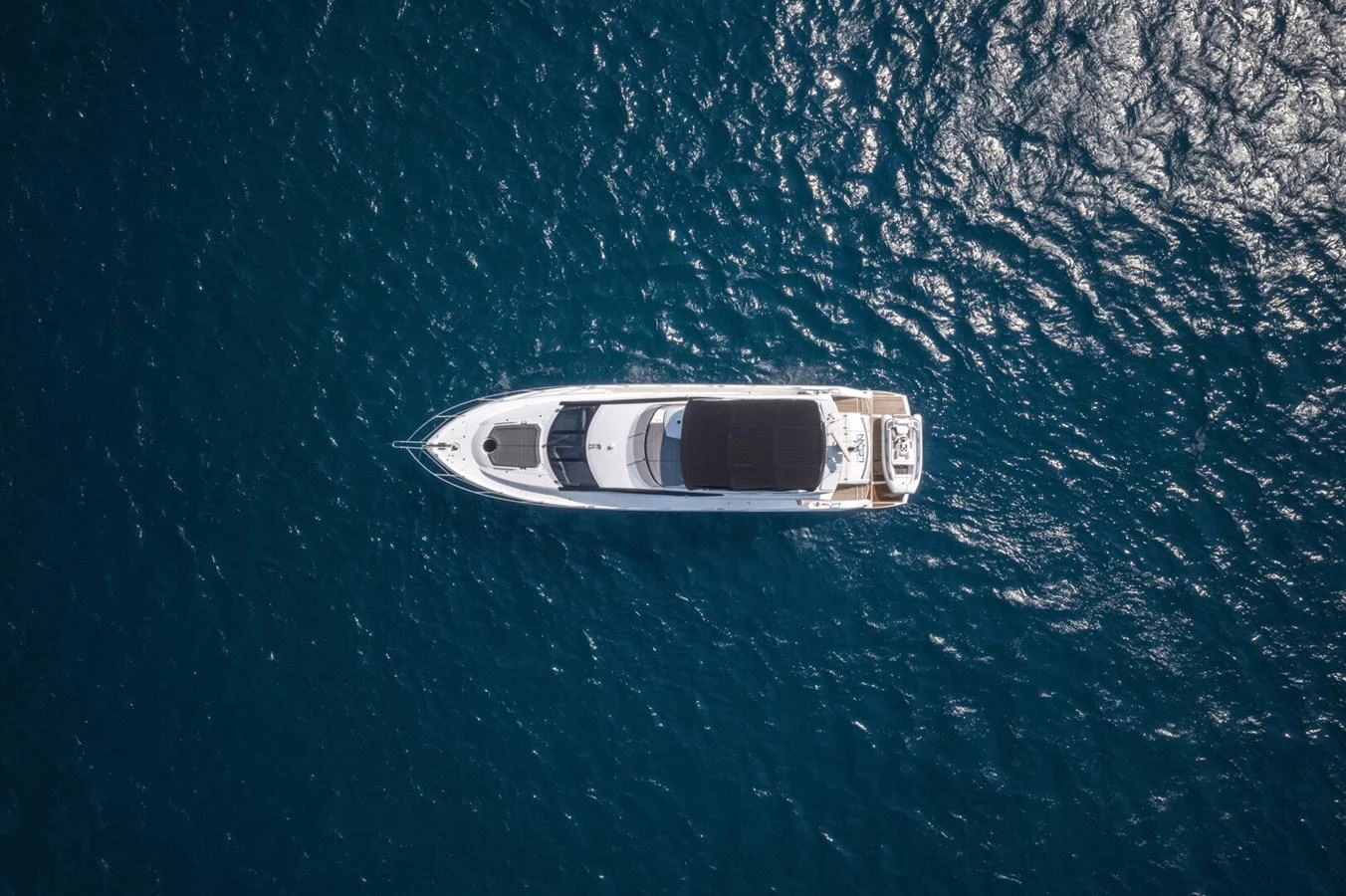 A sleek yacht cruises through deep blue waters, viewed from above. aboard "CORAZON DE LEON" Yacht for Sale