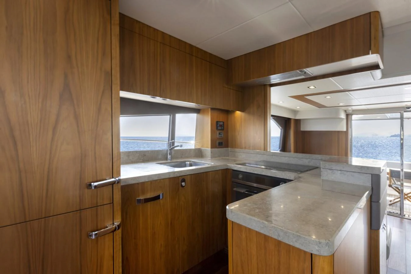 The yacht's galley features sleek wooden cabinetry and modern appliances with a view of the sea. aboard "CORAZON DE LEON" Yacht for Sale
