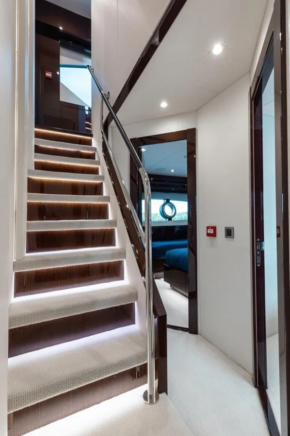A modern yacht interior featuring a sleek staircase with ambient lighting and a glimpse into a cozy stateroom. aboard 95 FT 2018 SUNSEEKER 95 YACHT, MIRRACLE Yacht for Sale
