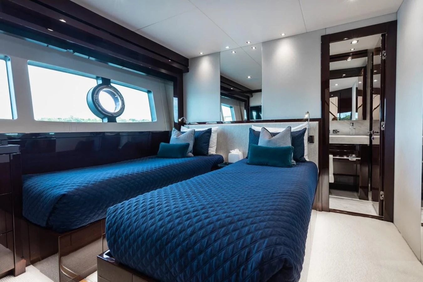 The guest stateroom features twin beds with elegant blue bedding and a modern ensuite bathroom. aboard 95 FT 2018 SUNSEEKER 95 YACHT, MIRRACLE Yacht for Sale