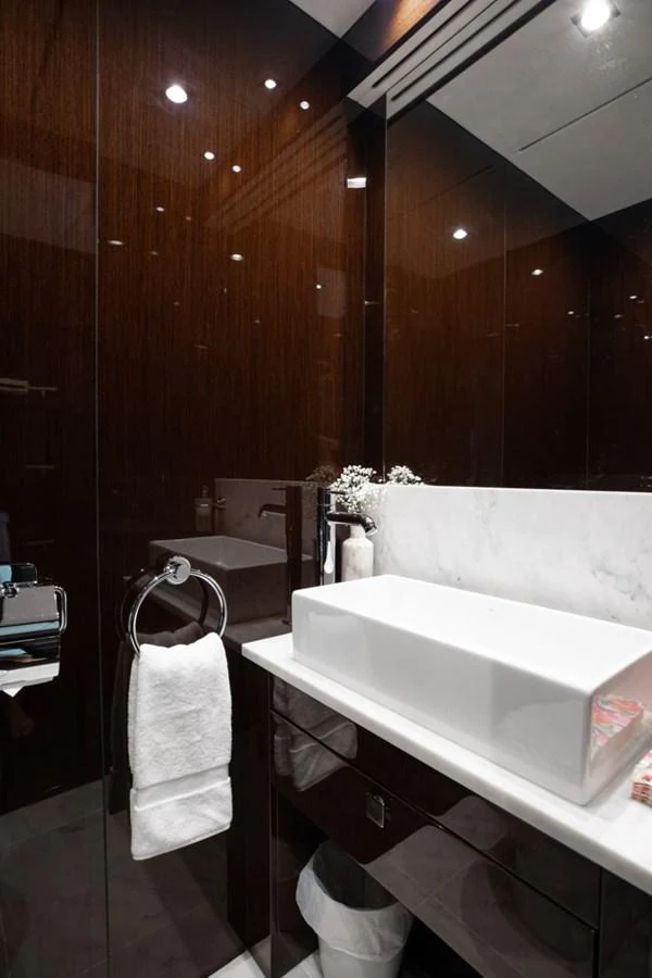 The yacht's bathroom features a sleek, modern design with dark wood finishes and a stylish rectangular sink. aboard 95 FT 2018 SUNSEEKER 95 YACHT, MIRRACLE Yacht for Sale