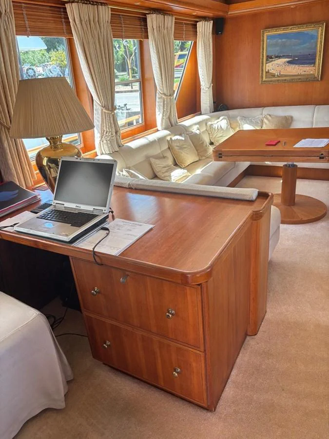 The salon features a cozy seating area with a wooden desk and large windows for natural light. aboard REX AQUILA Yacht for Sale