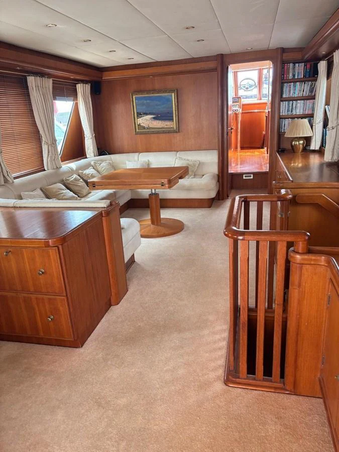 The salon features a cozy seating area with a wooden table and elegant decor. aboard REX AQUILA Yacht for Sale