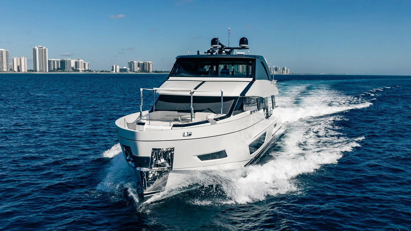 A sleek yacht cruises through the water with a cityscape in the background. aboard AQUASITION Yacht for Sale