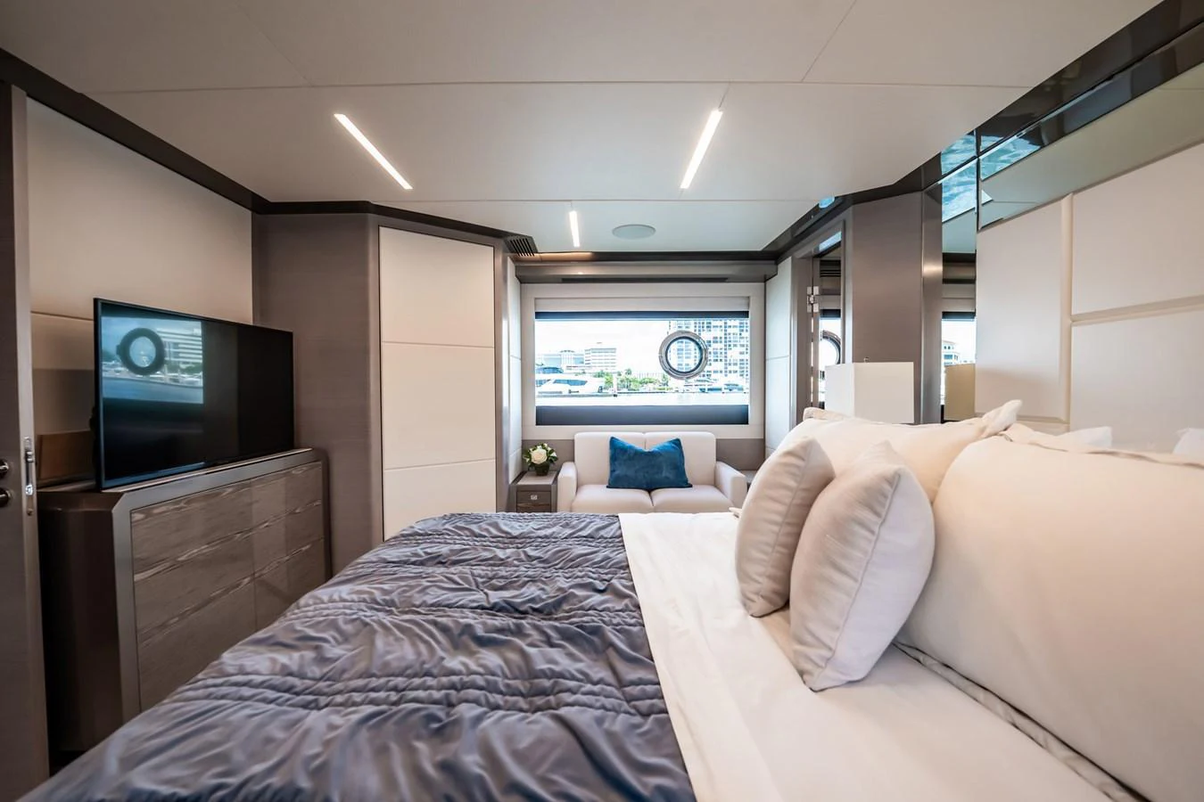 The stateroom features a plush bed, modern decor, and large windows offering a scenic view. aboard AQUASITION Yacht for Sale