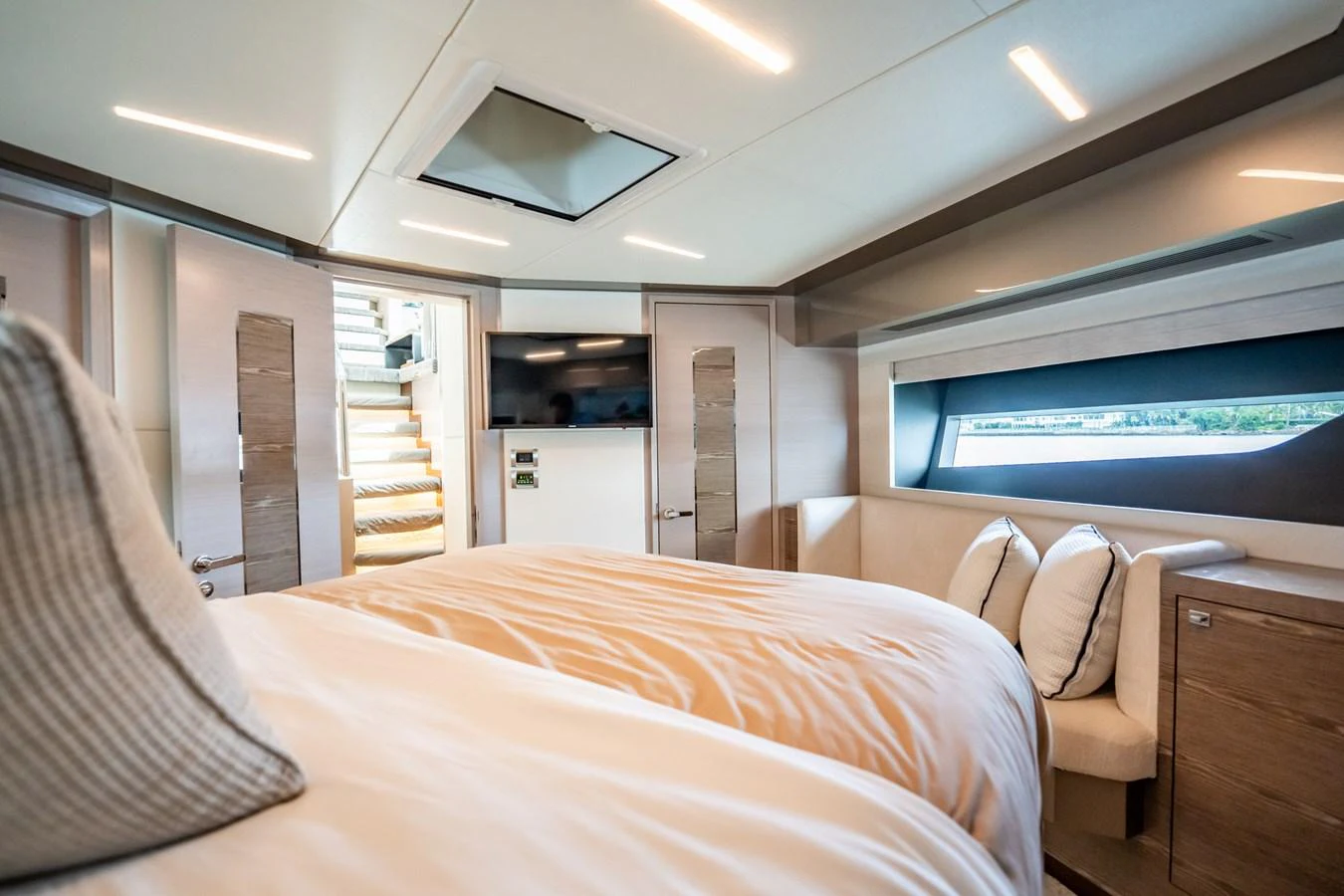 A luxurious stateroom featuring a large bed, modern lighting, and a scenic window view. aboard AQUASITION Yacht for Sale