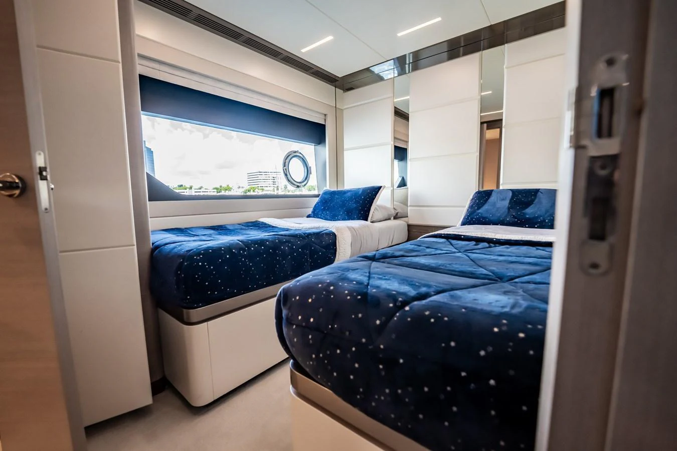 The guest stateroom features twin beds with luxurious bedding and a large window for natural light. aboard AQUASITION Yacht for Sale