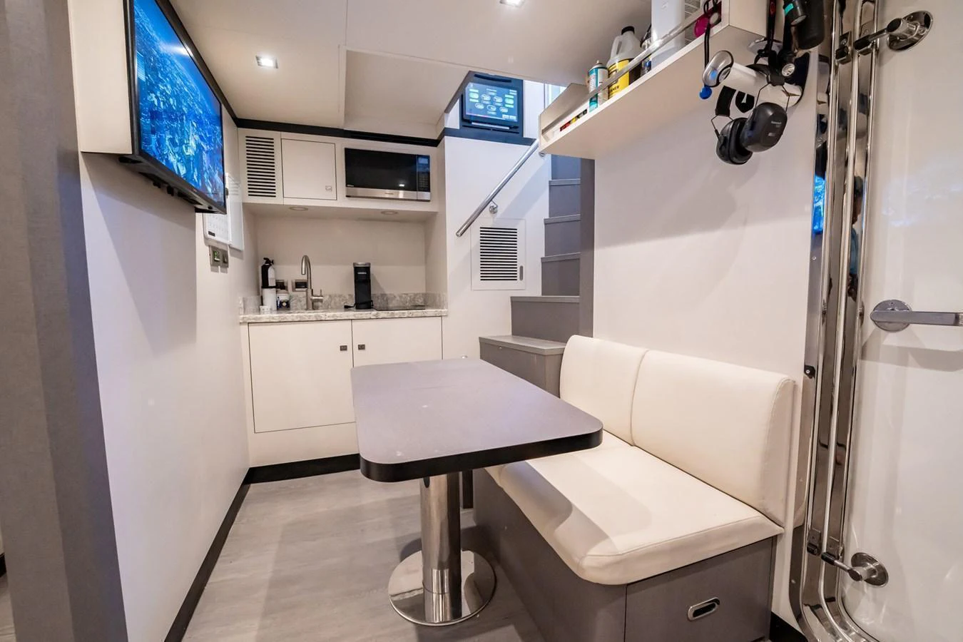 The yacht's galley features a cozy dining area with a table and bench seating, adjacent to a compact kitchen space. aboard AQUASITION Yacht for Sale
