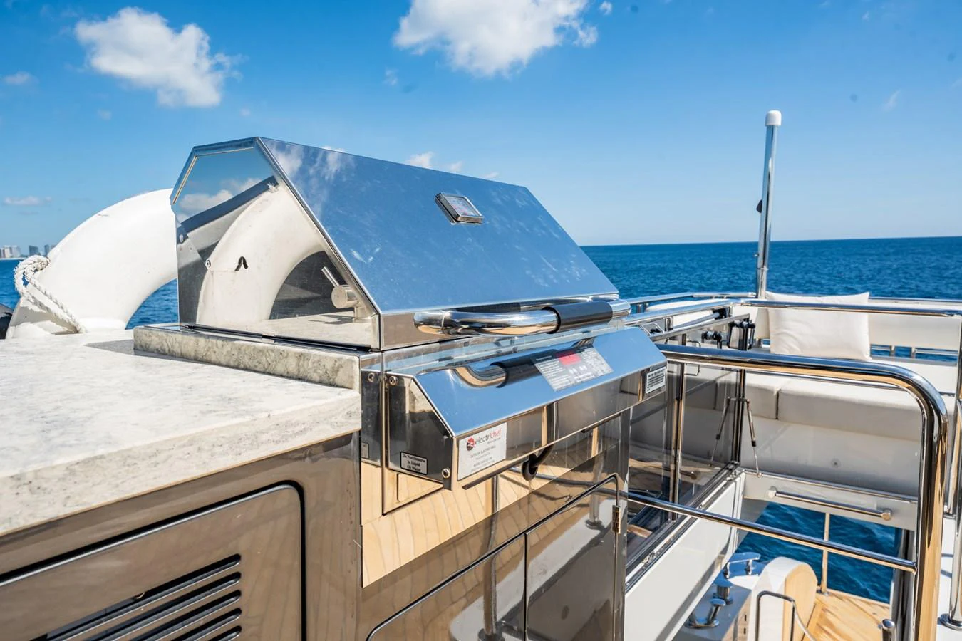 The yacht features a sleek outdoor grill area with a stunning ocean backdrop. aboard AQUASITION Yacht for Sale