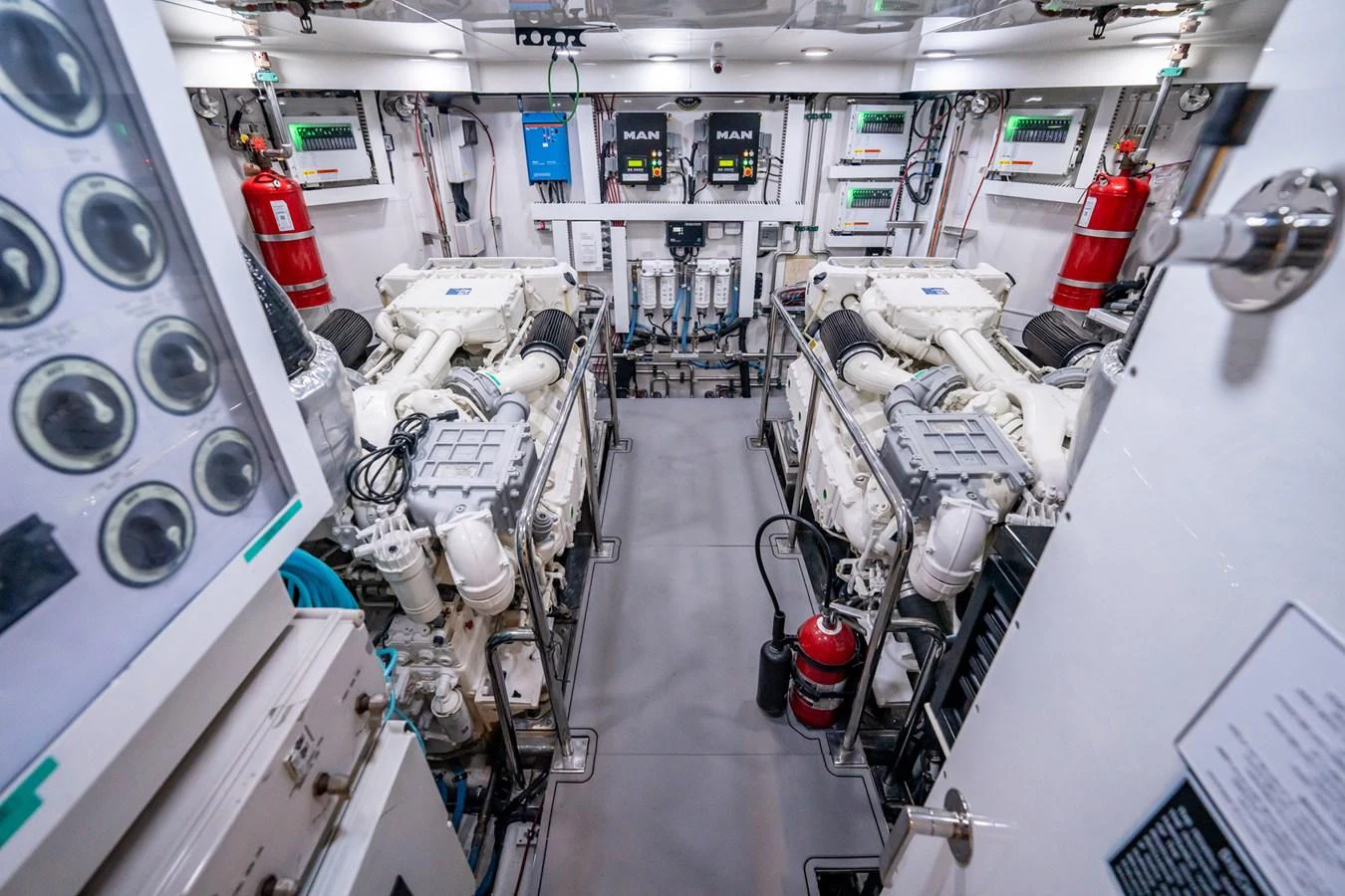 The image showcases a well-organized engine room with dual engines and various control panels. aboard AQUASITION Yacht for Sale