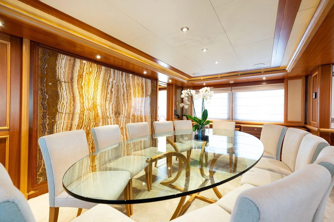 The yacht's dining area features a stylish glass table surrounded by plush chairs, set against a backdrop of rich wood and elegant decor. aboard EMOTION 2 Yacht for Sale