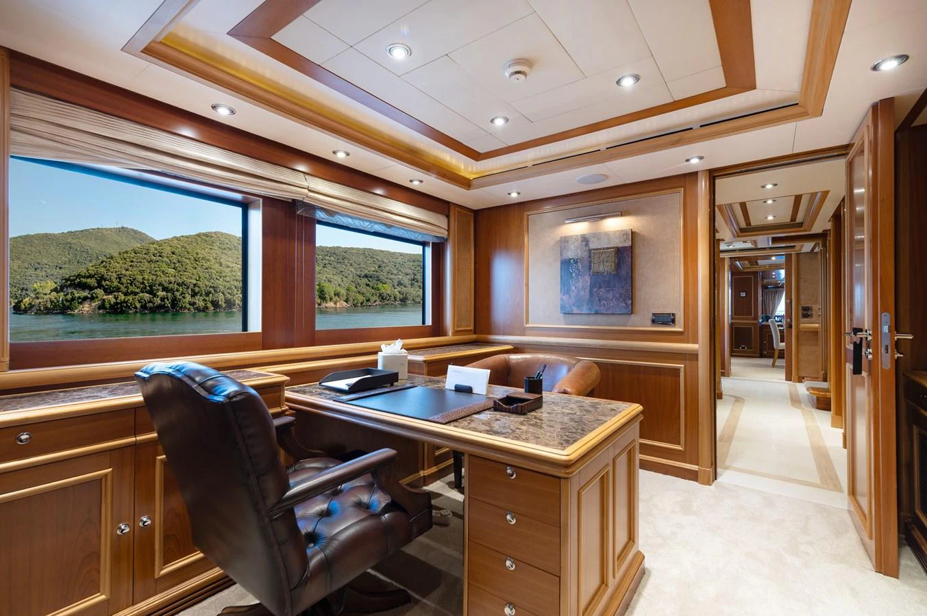 The yacht's office features elegant wood paneling, a large desk, and a scenic view through the window. aboard EMOTION 2 Yacht for Sale