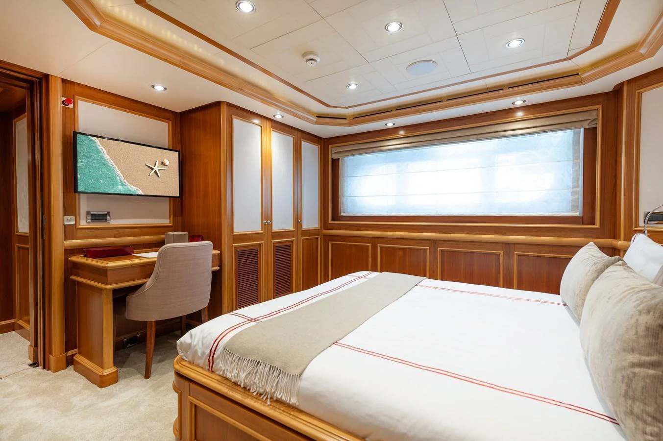 A luxurious stateroom featuring a comfortable bed, a desk, and elegant wood paneling. aboard EMOTION 2 Yacht for Sale