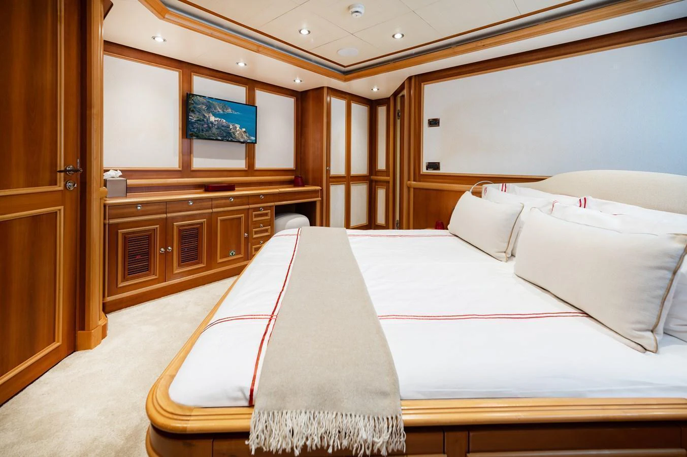 The stateroom features a luxurious bed with elegant wooden furnishings and a wall-mounted TV. aboard EMOTION 2 Yacht for Sale
