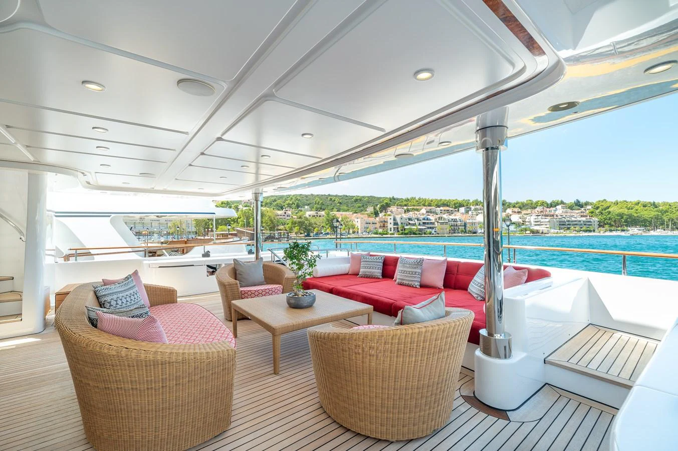 The aft deck features a spacious and inviting seating area with wicker chairs and a large red sofa, perfect for relaxation and socializing. aboard EMOTION 2 Yacht for Sale